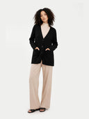 front view of a woman wearing a black v-neck cardigan over a beige mock neck sweater and wide-leg pants. #color_black