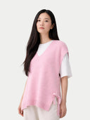 Woman wearing a pink sleeveless maternity sweater over a white shirt on a white background #color_almond-blossom