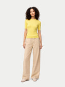 front view of a woman wearing a yellow top and beige pants on a white background #color_blazzing-yellow