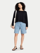 Woman wearing a black sweater and light blue denim shorts on a white background #color_black