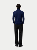 back view of a man wearing a navy blue sweater and black pants on a white background #color_mood-indigo