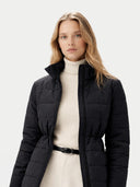Woman wearing a black puffer jacket over a white turtleneck sweater on a light gray background #color_black