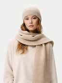 Woman wearing a beige knit hat and scarf on a white background #color_warm-grey