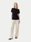 Woman wearing a black t-shirt and beige pants on a white background #color_black
