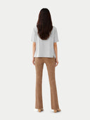 back view of Woman wearing a white top and brown pants on a white background #color_wind-chime