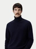 Man wearing a navy turtleneck sweater against a plain background #color_navy-blazer