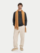 Man wearing a almond color scarf, dark shirt, beige pants, and shoes on a white background #color_almond