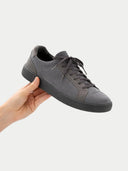 Gray sneaker held in a hand against a light gray background #color_frost-gray