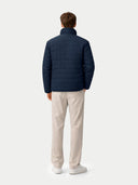 back view of man wearing a navy puffer jacket and beige pants on a white background #color_navy-blazer