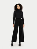 front view of a woman wearing a black turtleneck and wide-leg pants on a white background  #color_black