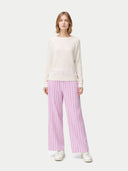 front view of a woman wearing a white long-sleeve cashmere sweater and pink striped pants on a white background #color_whisper-white