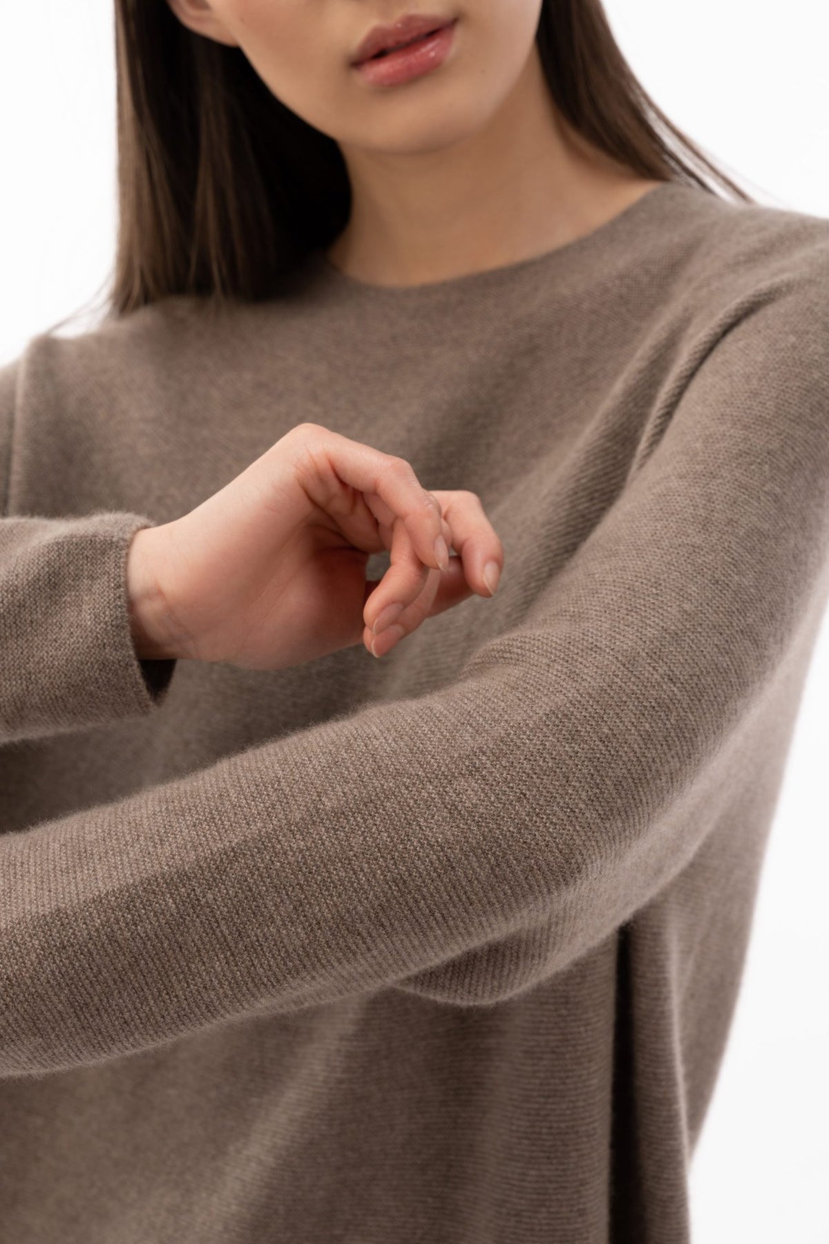 Close-up of a taupe seamless cashmere sweater, arms crossed, showing the uninterrupted knit