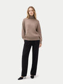 Woman wearing a brown sweater and black pants on a white background #color_taupe