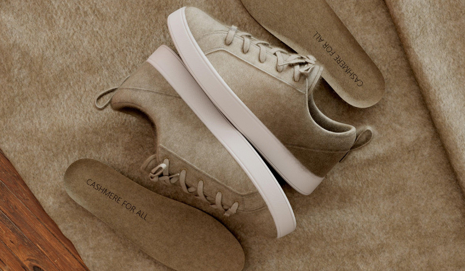 Pair of beige sneakers with white soles on a textured surface