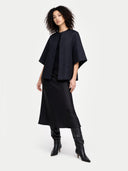 Woman wearing a black poncho jacket, dress, and boots on a white background #color_charcoal