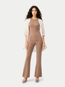 Woman wearing a brown ribbed jumpsuit with a white cardigan on a white background #color_timber-wolf
