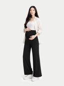 Woman wearing a white shirt, black maternity pants, and white sneakers on a white background  #color_black