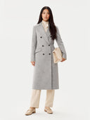 front view of a woman wearing a gray coat holding a beige clutch against a white background #color_vapor-blue