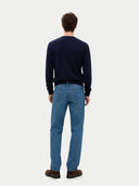 back view of a man wearing a navy sweater and blue jeans on a white background #color_navy-blazer