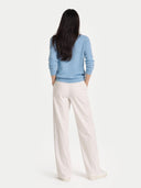 back view of person wearing a light blue sweater and white pants on a white background #color_light-blue