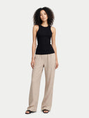 Woman wearing a black sleeveless top and beige pants on a white background #color_black