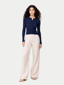 Woman wearing a navy blue top and white pants on a white background #color_mood-indigo