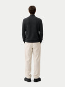 back view of a Person wearing a black sweater and white pants on a light gray background #color_charcoal
