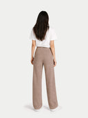Back view of a woman wearing a white top and beige pants on a light gray background #color_taupe