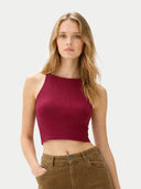 Woman wearing a burgundy ribbed tank top and brown pants on a light gray background #color_dry-rose