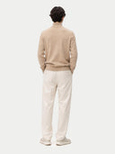 back view of a person wearing a beige sweater and white pants on a white background #color_warm-grey