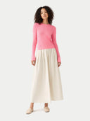 Woman wearing a pink sweater and beige skirt on a white background #color_shell-pink