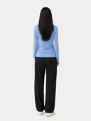 Person wearing a light blue sweater and black pants on a white background #color_della-robbia-blue