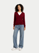 Woman wearing a red cardigan, white shirt, blue jeans, and white sneakers on a white background #color_bordeaux