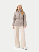 Woman wearing a gray puffer jacket and white pants on a light gray background #color_cement