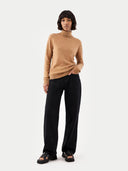 woman wearing an almond color turtleneck sweater and black pants. #color_sheepskin