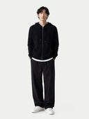 Person wearing a black hoodie and pants with white shoes on a white background #color_black