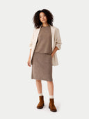 Woman wearing a beige cardigan, brown sweater, and skirt with brown boots on a white background #color_taupe