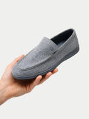 Gray slip-on shoe held in a hand against a light gray background #color_steel-gray