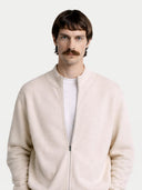 Man wearing a light beige bomber jacket over a white shirt on a plain background #color_marshmallow