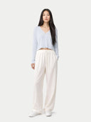 Woman wearing a light blue crop cardigan and white pants on a white background #color_ice-flow