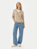 front view of Woman wearing a beige sweater and blue jeans on a white background #color_warm-grey