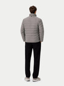 back view of a man wearing a gray puffer jacket and black pants on a white background #color_dim-gray