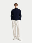 front view of a man wearing a navy sweater and white pants on a light gray background #color_navy-blazer