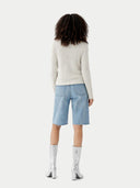 Person wearing a light-colored sweater and light blue shorts on a white background #color_whisper-white