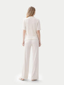 back view of a woman wearing a white outfit on a light gray background #color_whisper-white