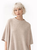 Woman wearing a beige poncho against a white background #color_biscotti