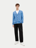front view of a man wearing a blue v-neck cardigan with pockets over a white t-shirt and black pants on a white background #color_blue