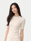 Woman wearing a white ribbed knit top against a light gray background #color_whisper-white
