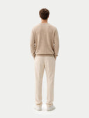 back view of a man wearing a beige sweater and pants on a white background #color_warm-grey