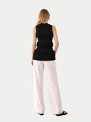 back view of a black sleeveless top and white pants on a white background #color_black